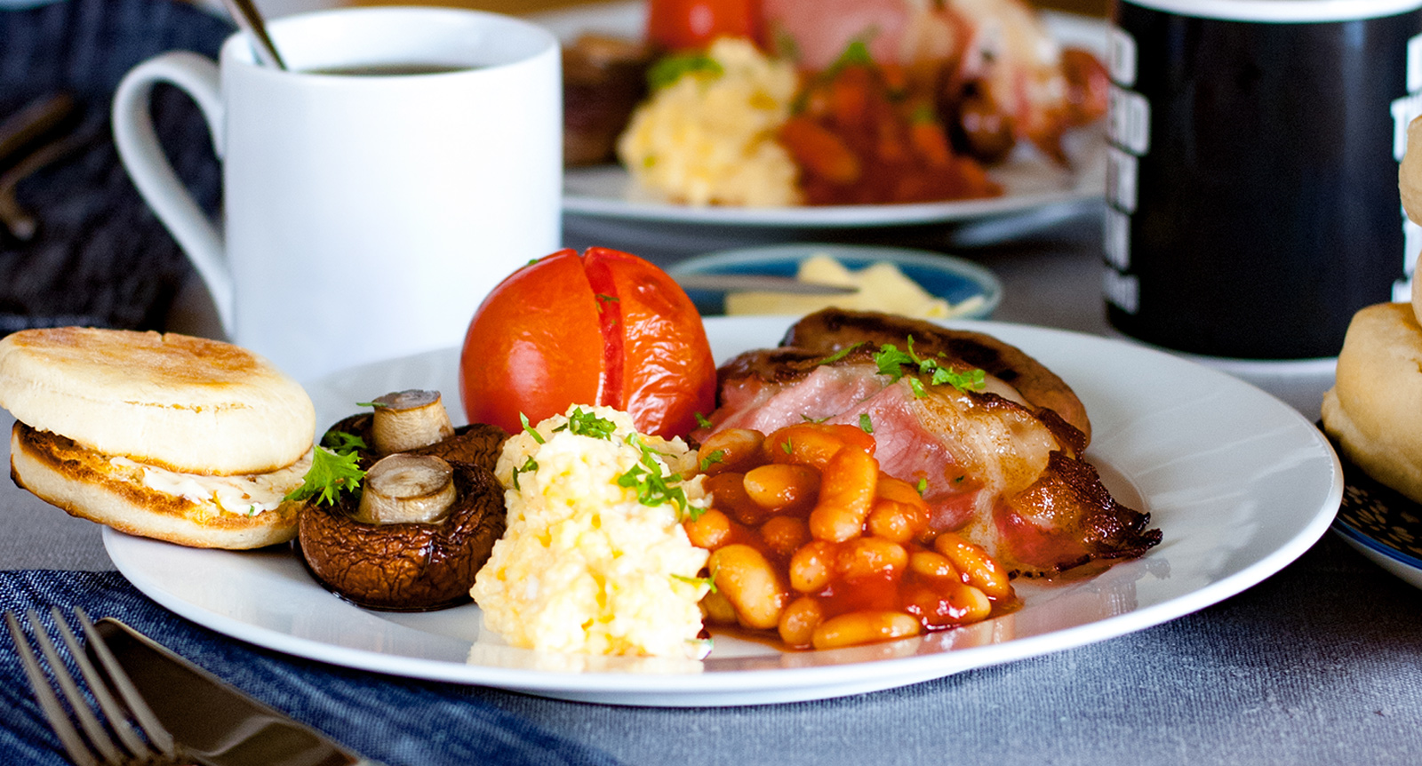 Klassisk engelsk frukost med äggröra, korv och vita bönor