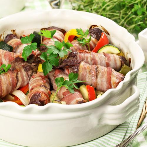 Baconlindade lövbiffsrulader på grönsaksbädd