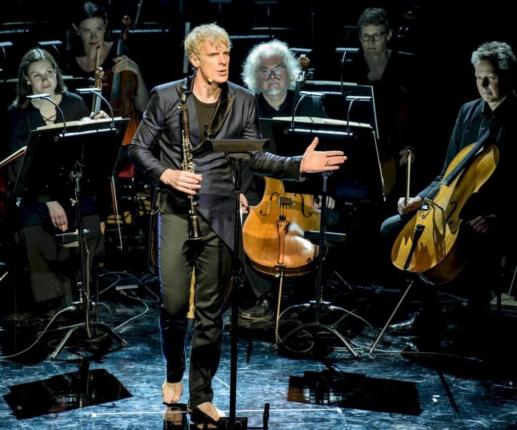 Martin Fröst spelar klarinett barfota på scenen med orkester.