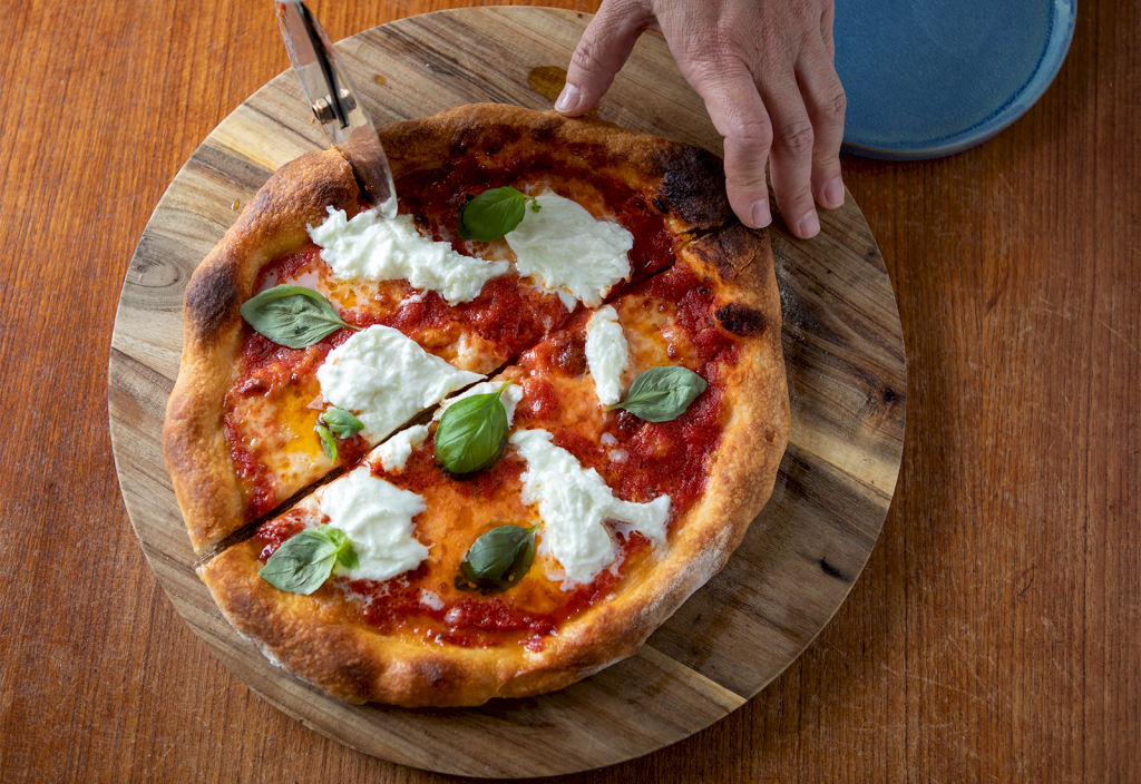Pizza margherita delas med pizzadelare.