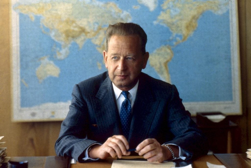 Dag Hammarskjöld sitter framför en världskarta. 