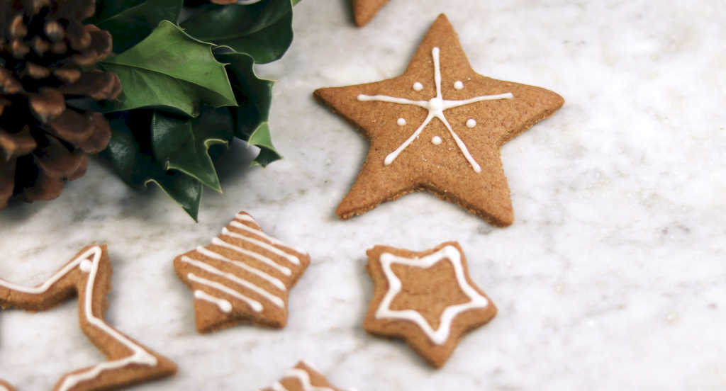 Pepparkakor med stjärnform och vit glasyr ligger på marmor.