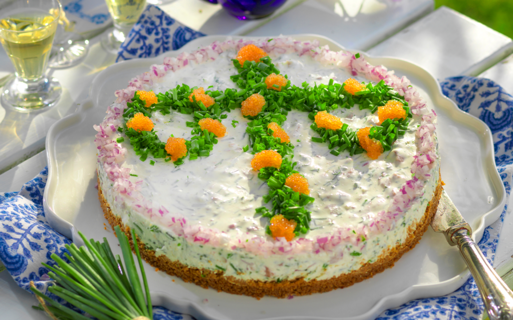 Tårta med matjessill dekorerad med midsommarstång av dill och rom.